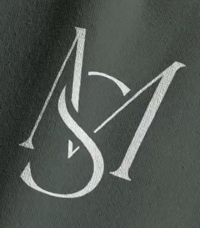 Dark green fabric with a white embroidered graphic of the initials S M